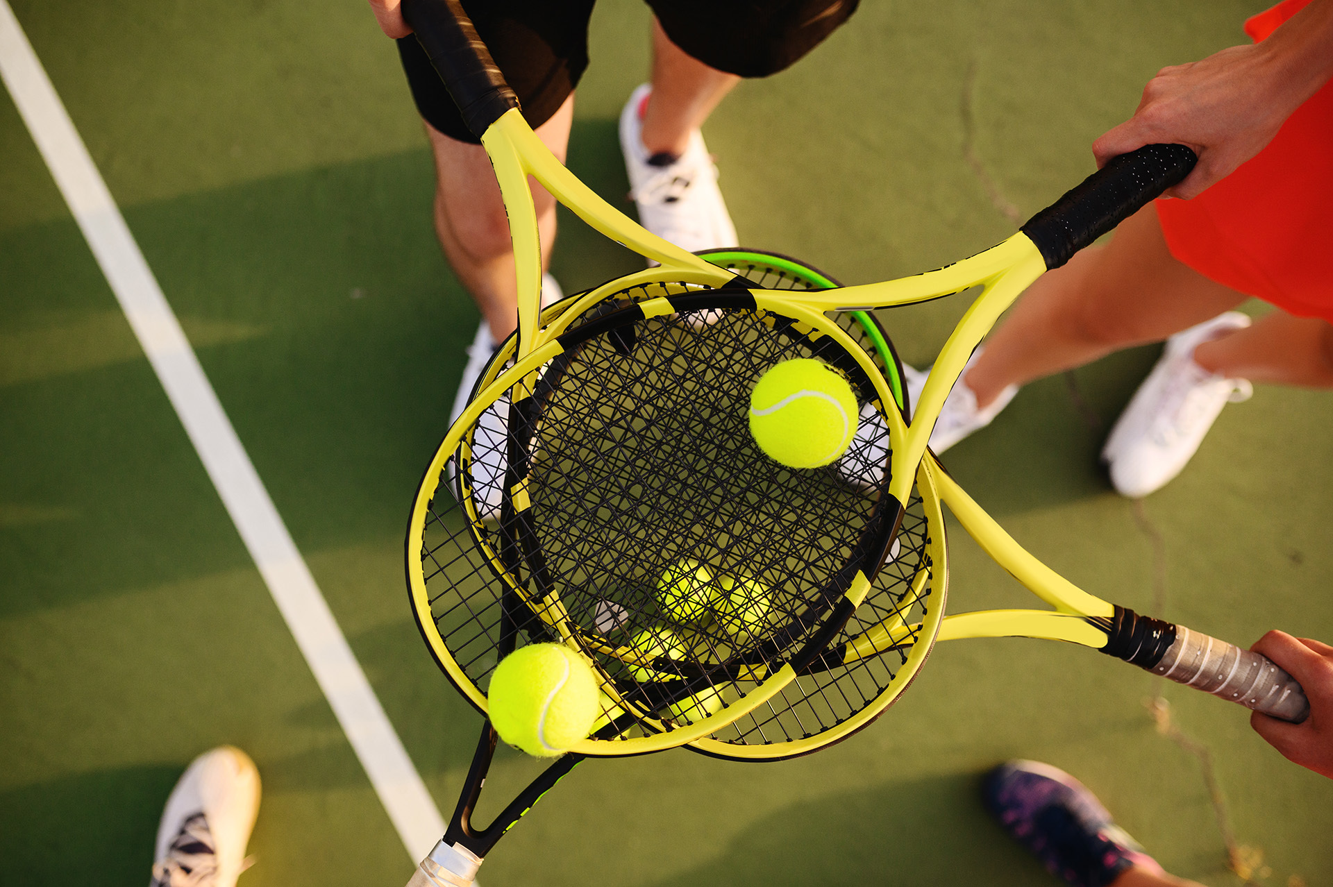 Tennisrackets und Tennisbälle auf einem Tennisplatz, umgeben von Spielern – typisch für das Vereinsleben im Tennisclub Schwarz-Weiß Montabaur e.V.