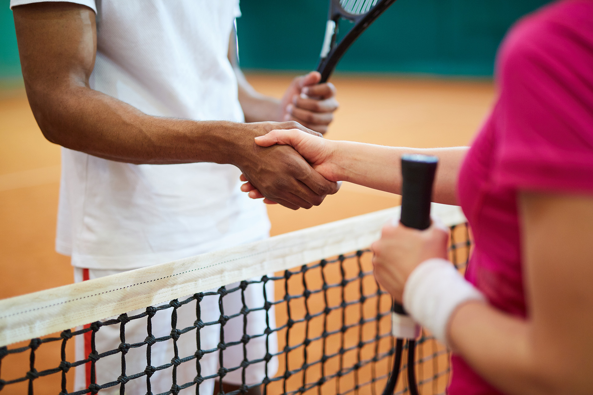 Zwei Tennisspieler schütteln sich über das Netz die Hände nach einem Tennismatch.